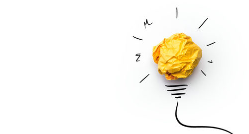 A crumbled piece of yellow paper surrounded by drawn lines to depict a light bulb.